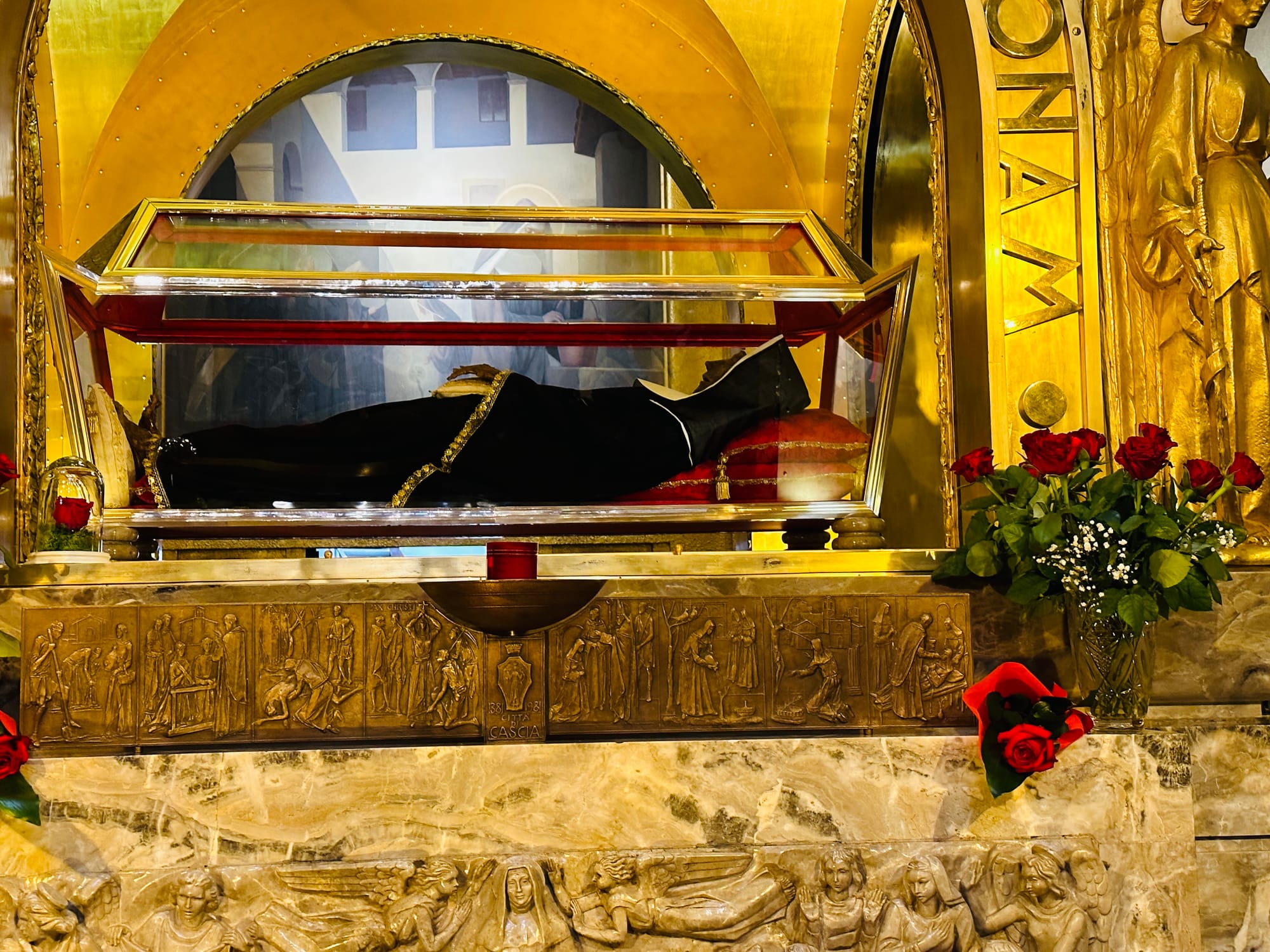 St. Rita's incorrupt body in the Basilica in Cascia, Italy with detailed carvings on front and roses.